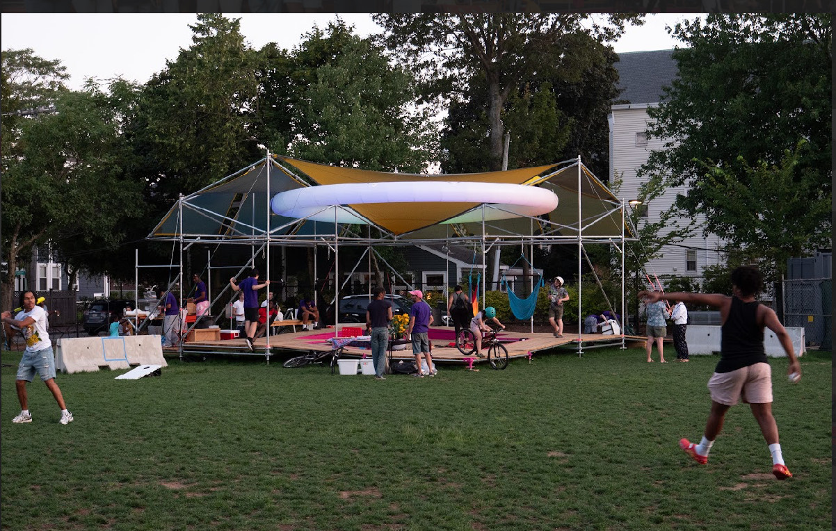 Image of SHADE installation in Sennott Park with many people playing in the grass and seated on the structure