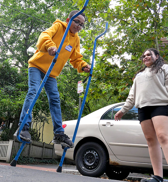 A child walking on stilts and someone watching