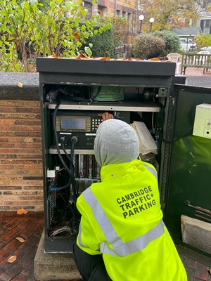 A member of the Cambridge Traffic, Parking, and Transportation Department works on a traffic signal box on Garden Street.