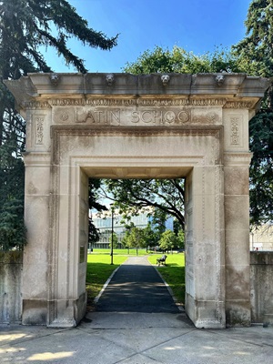 tan arch way leading to green lawn with library in background