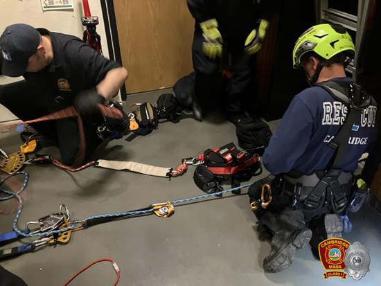 firefighteres in harnesses and protective clothing set up a rope rescue system prior to entierin the elevator shaft to rescue a victim