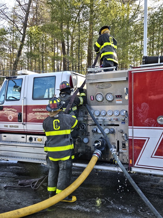 Recruit firefighters repacking hose on the pump at MA Fire Academy burn training