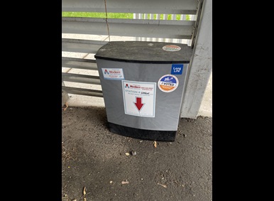 Smart box rat trap on the ground with a Participatory budgeting sticker on it
