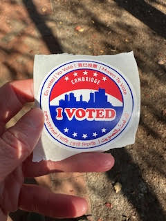 A hand holding a City of Cambridge "I Voted" sticker
