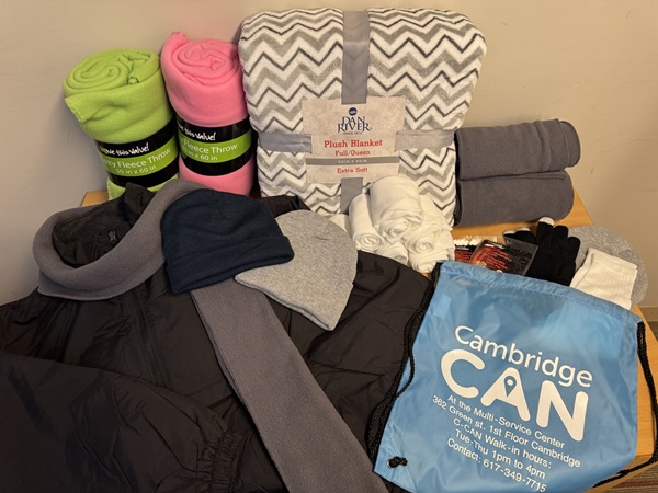 Blankets, sweaters, socks, hats, gloves, and other cold and wet weather supplies laid out on a table.