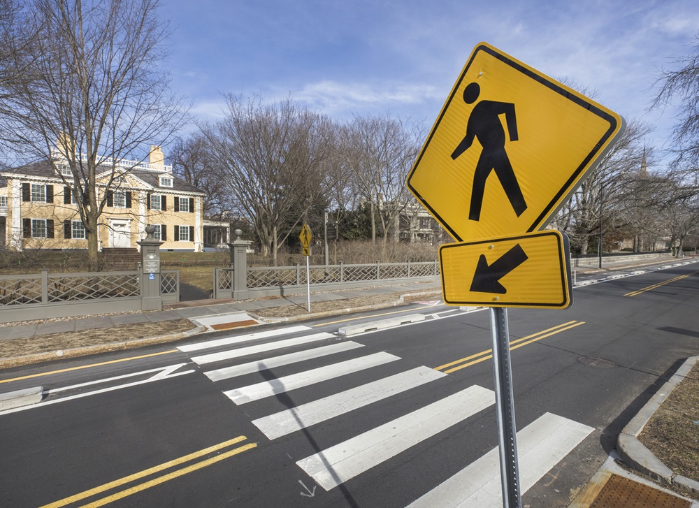 A street sign emphasizes the presence of a crosswalk to vehicles driving by