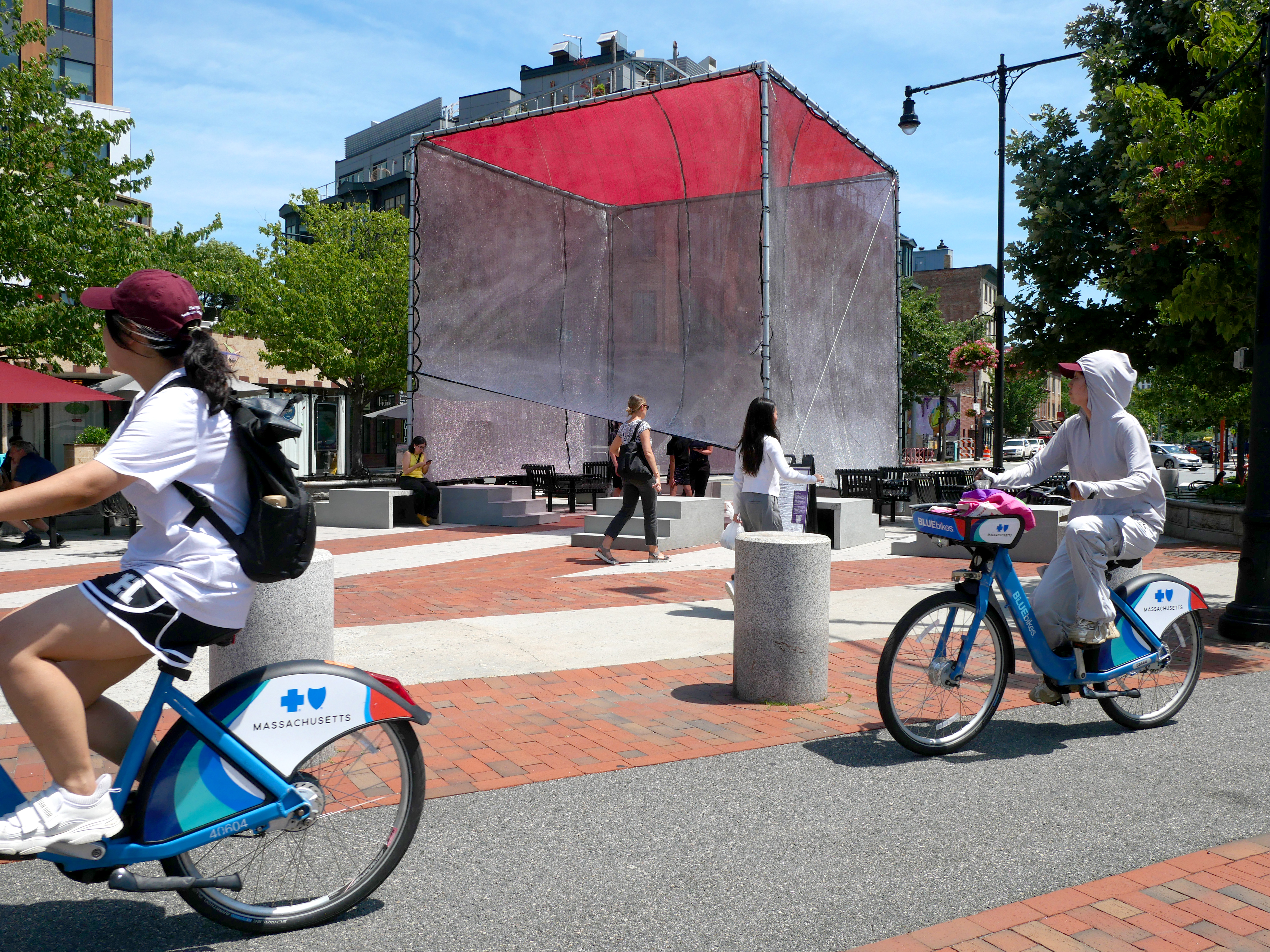 local plaza with a shade structure and bicycles passing by