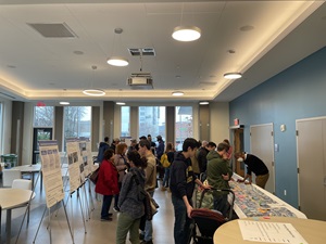 About 25 people in a room with informational boards and a project map with sticky notes.