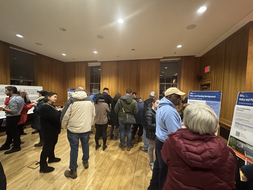 room with people standing around looking at boards and maps