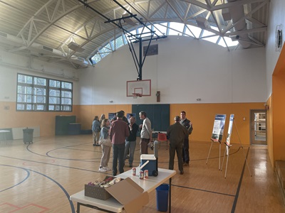 Basketball gym with people standing around look at boards