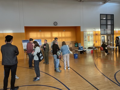 Basketball gym with people standing around look at boards