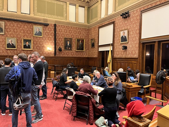 Participatory Budgeting volunteers work in groups in the Sullivan Chamber of City Hall