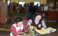 Two children sitting at a table reading books