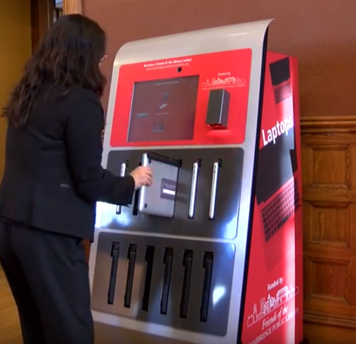 Person taking a laptop from a laptop kiosk