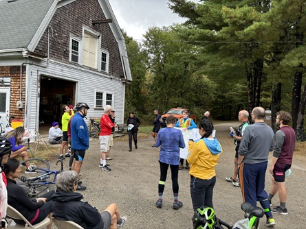 People gather at the CWD barn and learn about the watershed. A staff member stands behind a poster map talking to those gathered.